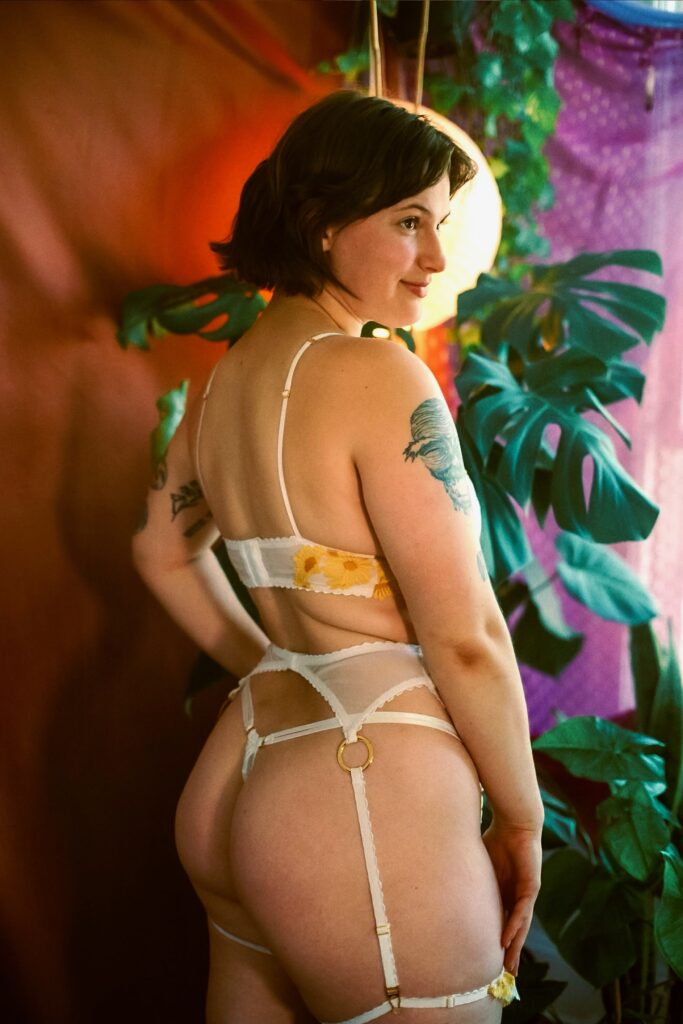 A full body photo of Milwaukee companion Ivy Maxwell. Ivy is wearing a three piece lingerie set, her curvy bottom visible. A circular light artistically surrounds her head, almost like a halo.